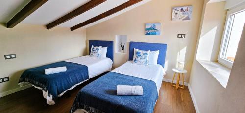阿尔卡拉利Casa Galia的一间卧室配有两张蓝色床罩和窗户。