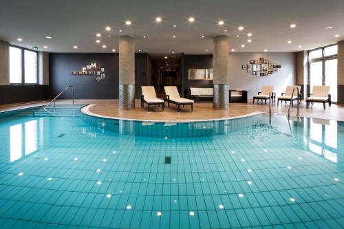 莱比锡Pentahotel Leipzig的一座配有桌椅的酒店游泳池