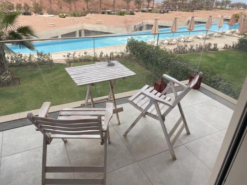 艾因苏赫纳Beautiful chalet in Il Monte Galala المونت جلالة ch15-01-01的阳台设有两把椅子和一张桌子,享有游泳池的景色