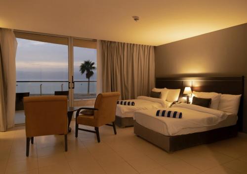 索瓦马O Beach Hotel & Resort的酒店客房带两张床和一张桌子以及椅子。