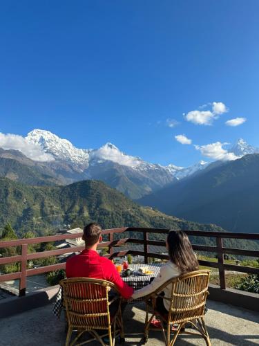 AstamHill Top Lodge Ghandruk的坐在桌子上的男人和女人,享有山景