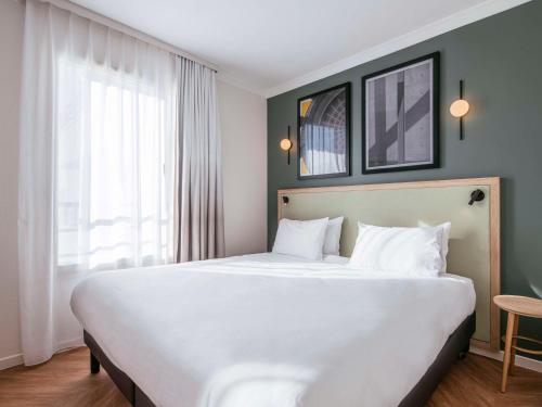 巴黎巴黎肖蒙山丘阿德吉奥公寓式酒店的窗户客房内的一张大白色床