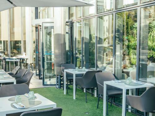 巴黎铂尔曼度假巴黎埃菲尔铁塔酒店的餐厅设有桌椅和窗户。