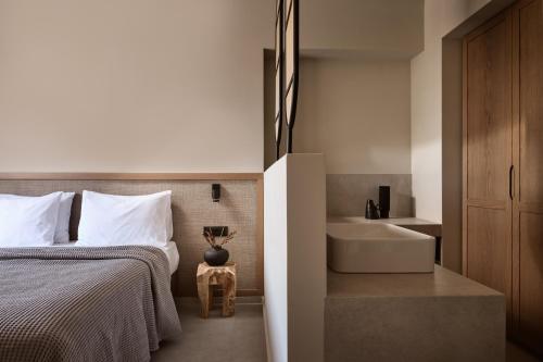 蒂锡利维Alamis Hotel & Apartments的一间卧室配有一张床、一个浴缸和一个水槽