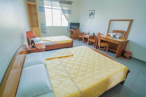 龙川市Nhà Hàng Khách Sạn Hòa Bình 2的一间卧室配有一张床和一张书桌,还有一间用餐室