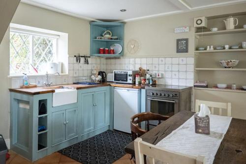 托玛斯镇The Rose Cottage的厨房配有蓝色橱柜和桌子