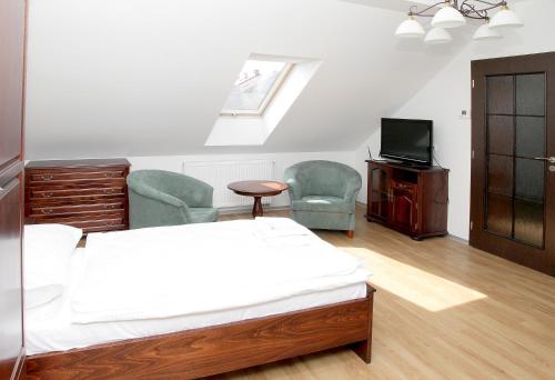 捷克特热博瓦Pivovar a restaurace Faltus的一间卧室配有一张床、两把椅子和一台电视