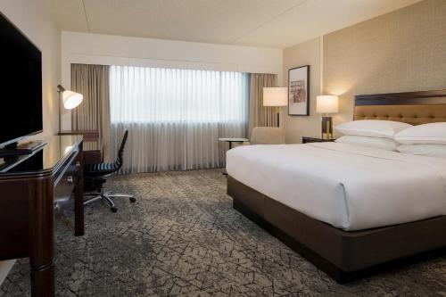 罗缪勒斯底特律大都会喜来登酒店机场店的酒店客房设有一张大床和一张书桌。