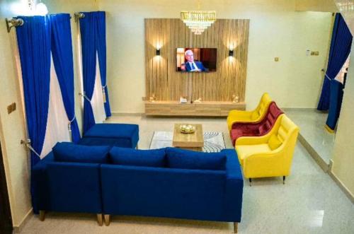 阿库雷Enny'scourt Service Apartment的客厅配有蓝色的沙发和2把黄色的椅子