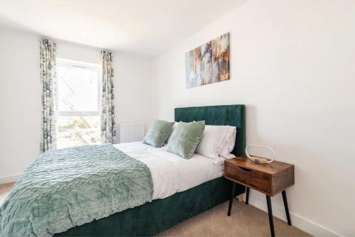 SwanscombeLuxury Modern 2 Bed Apartment in Ebbsfleet - 20mins from London的一间卧室配有一张带绿色床头板的床和一张桌子