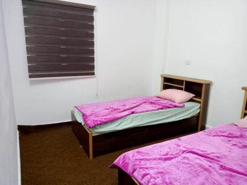 阿杰隆عجلون- راس منيف的一间卧室设有两张带粉色床单的床和窗户。