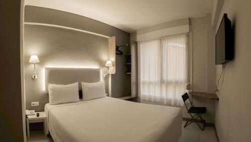 毕尔巴鄂比尔比酒店的卧室设有一张白色大床和一扇窗户。
