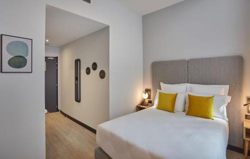 尼姆Odalys City Nîmes Arènes的卧室配有一张带黄色枕头的大型白色床。