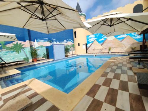 San Juan del ParanáHotel Villa的一个带两把遮阳伞和棋盘楼层的游泳池
