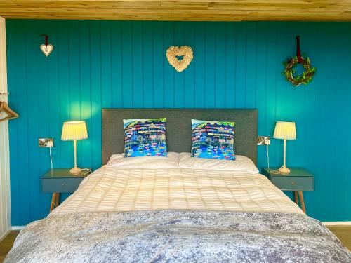阿博伦The Pod & Cwtch luxury accommodation的一间卧室配有一张蓝色墙壁的床和两盏灯。