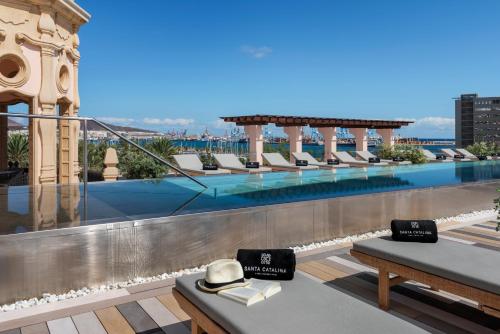 大加那利岛拉斯帕尔马斯Santa Catalina, a Royal Hideaway Hotel的酒店屋顶设有游泳池和椅子