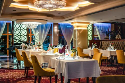 斯利亚奇Wellness & Spa Hotel Kaskady的餐厅配有白色的桌椅和吊灯