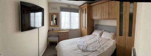 亨斯坦顿Luxurious Beach Resort & Golf Club的一间卧室配有一张床、一张书桌和一台电视