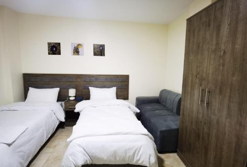 瓦迪穆萨Hospitality apartments的一间带两张床和一张沙发的客厅
