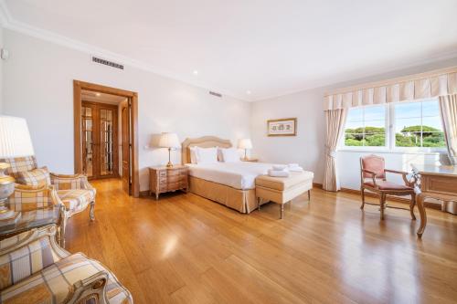 金塔湖Extraordinary Villa on an elevated position in Quinta do Lago的卧室配有一张床和一张桌子及椅子
