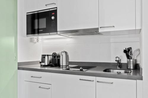 洛桑Sallaz Residence by Homenhancement的白色的厨房配有水槽和微波炉