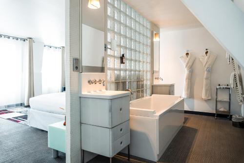 巴黎Kube Hotel Paris的白色的浴室设有水槽和浴缸。