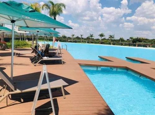 比勒陀利亚Luxury beach lagoon 1 Bedroom apartment的一个带躺椅和遮阳伞的游泳池