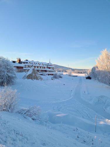 ÖverkalixArctic Circle Cabin的雪覆盖的田野,背景是一座建筑
