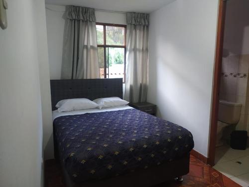 阿亚库乔HOSPEDAJE EL ARCO的一间卧室配有一张带蓝色棉被的床和窗户。