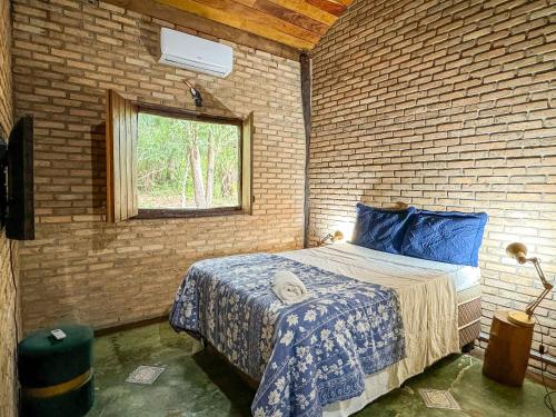 博尼图Chalés Pocoó com rio exclusivo的卧室配有砖墙内的床铺