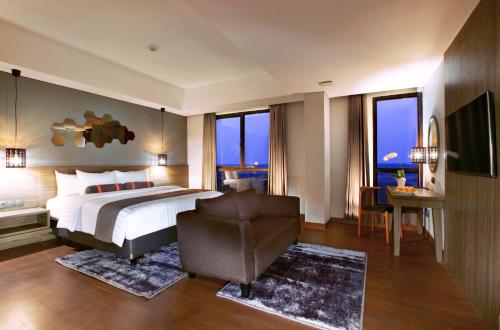 普哇加达Harper Purwakarta by ASTON的一间卧室配有一张床、一把椅子和窗户。