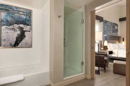 库比蒂诺库珀蒂诺希尔顿花园酒店的一间带玻璃淋浴间的浴室和一间卧室
