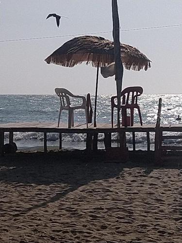 RincónCanadian House Rincón del Mar的海滩上的桌椅和遮阳伞