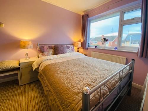 切尔滕纳姆Purple dream double bedroom的一间卧室设有一张大床和一个窗户。