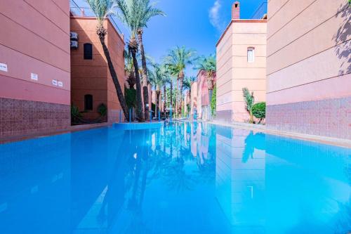 马拉喀什RIAD TAWSALANE的棕榈树两栋建筑之间的游泳池