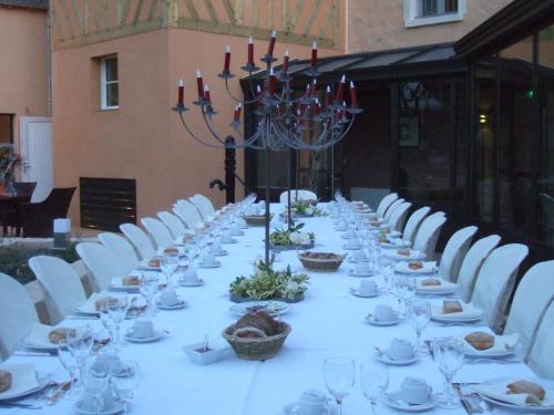 彻尔维尔圣欧班酒店的一张长桌,配有白色的椅子和盘子,酒杯