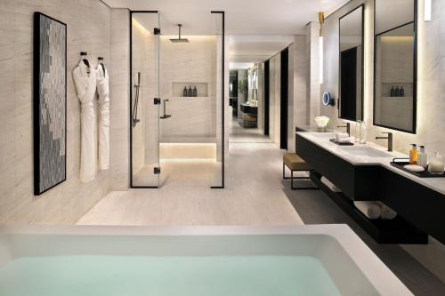 迪拜迪拜喜来登大酒店的带浴缸、两个盥洗盆和淋浴的浴室。
