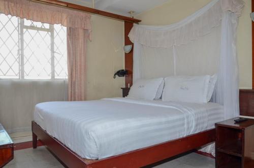 内罗毕Blue Hut Hotel的卧室内的一张带白色床单和枕头的床