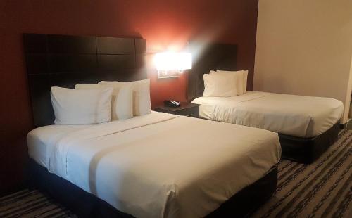 亨博尔Red Roof Inn & Suites Houston – Humble/IAH Airport的酒店客房,配有两张带白色床单的床