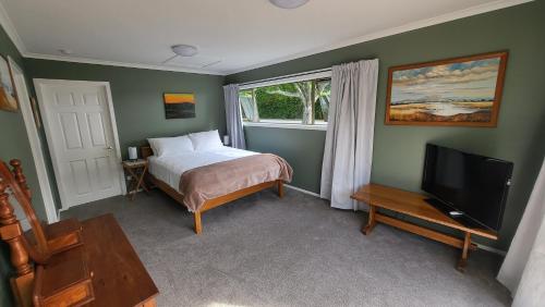 哈士汀Dewdrop Cottage的一间卧室配有一张床和一台平面电视