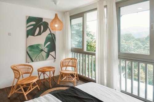 茂物Villa Jenis By The Villas 100的带两把椅子的卧室和带窗户的阳台