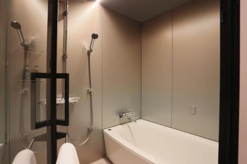 东京NOHGA HOTEL UENO TOKYO的浴室配有浴缸、淋浴和镜子