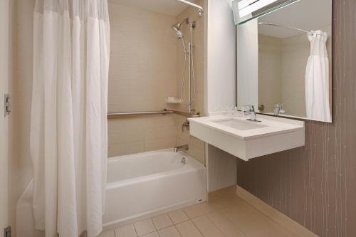 奥斯汀奥斯丁大学区万怡酒店的白色的浴室设有水槽、浴缸和淋浴。