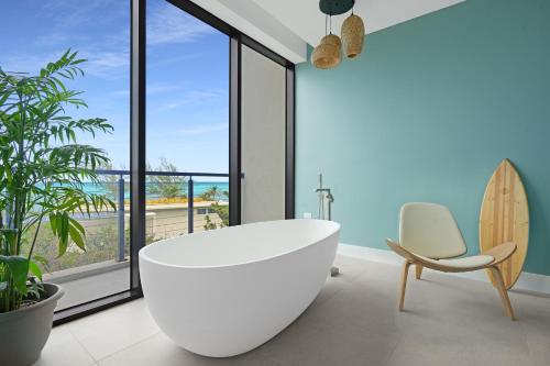 西湾VIDA Cayman的浴室设有白色浴缸、椅子和冲浪板