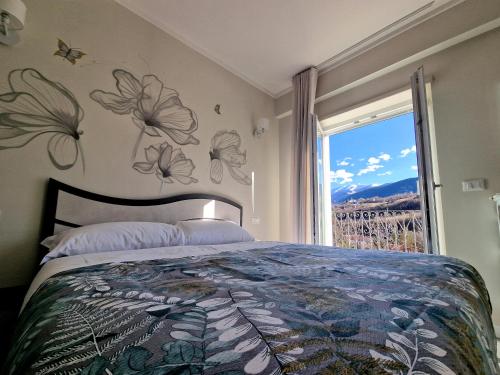 拉奎拉Il Filo Rosso的一间卧室设有一张床,墙上设有鲜花窗户。