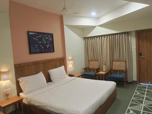 乌贾因Hotel Ashray的酒店客房,配有一张床和两把椅子