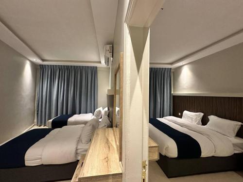 亚喀巴Aladnan hotel的配有衬衫的酒店客房内的两张床