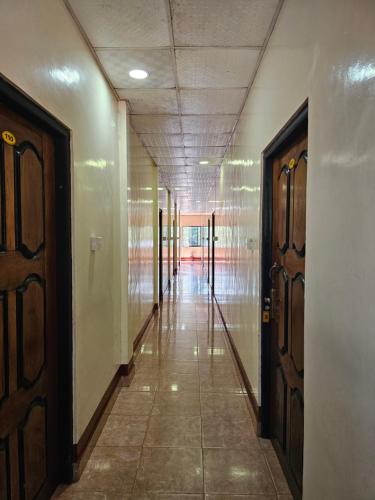 KilinochchiHotel SELLA & Rest的空的走廊,有两扇门,铺着瓷砖地板