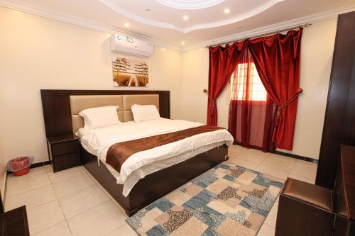 An NimāşTaraf Al Asalah Villas的一间卧室配有床和红色窗帘