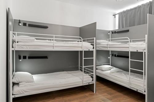 布加勒斯特Nest Boutique Hostel的客房设有三张双层床,配有白色床单
